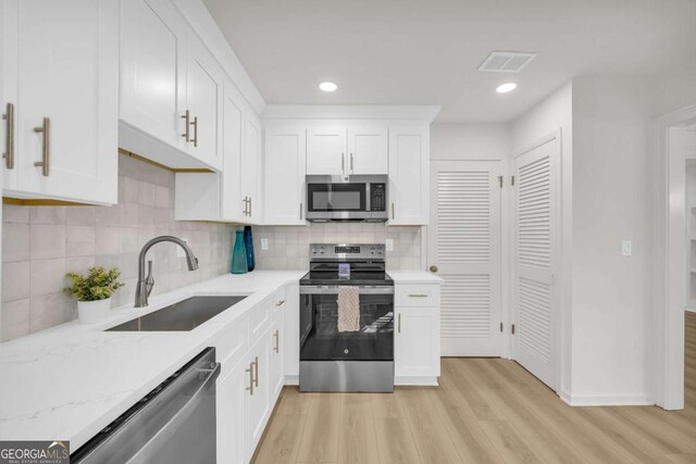 1 N Boundary Pl NW, Atlanta, GA 30318 - kitchen featuring stainless steel appliances, a sink, light wood-style floors, white cabinets, and decorative backsplash