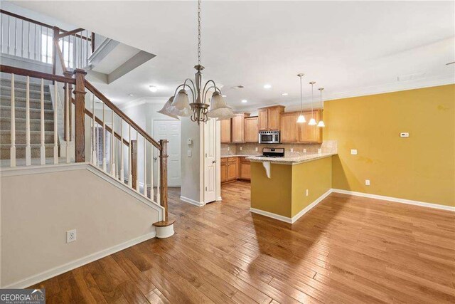 100 Trailside Way, Hiram, GA 30141 - kitchen with appliances with stainless steel finishes, a chandelier, baseboards, a peninsula, and ornamental molding