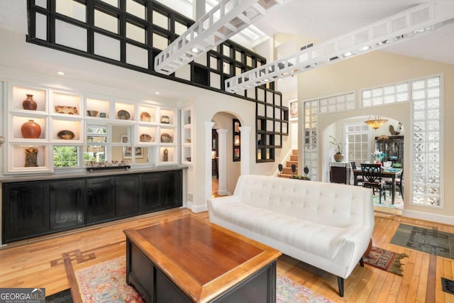 228 Clarion Ave, Decatur, GA 30030 - living room with arched walkways, light wood-style floors, stairs, a high ceiling, and baseboards