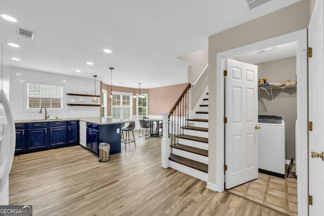 502 Stoneland Pl, Lawrenceville, GA 30046 - kitchen featuring blue cabinets, washer / clothes dryer, a peninsula, open shelves, and a kitchen breakfast bar
