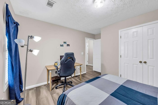 502 Stoneland Pl, Lawrenceville, GA 30046 - bedroom featuring wood finished floors, baseboards, a closet, a textured ceiling, and an office area