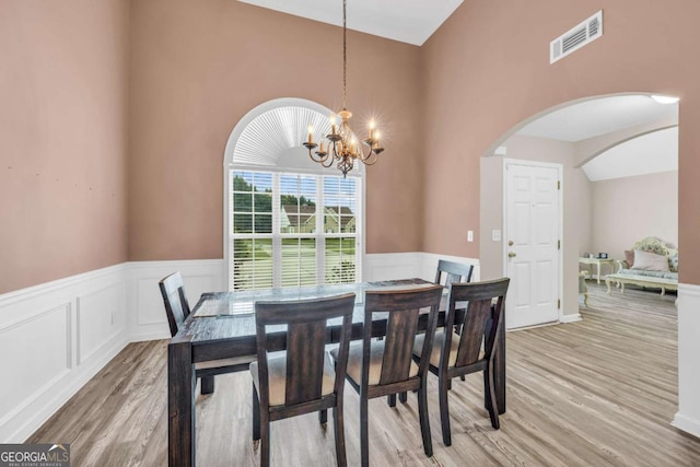502 Stoneland Pl, Lawrenceville, GA 30046 - dining space with light wood-type flooring, arched walkways, a wainscoted wall, and a chandelier