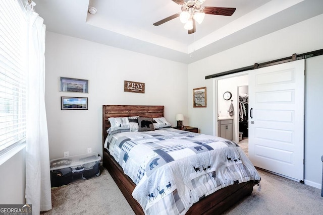 174 Silver Birch Pass, Newnan, GA 30265 - bedroom with a barn door, carpet floors, a raised ceiling, a ceiling fan, and a spacious closet