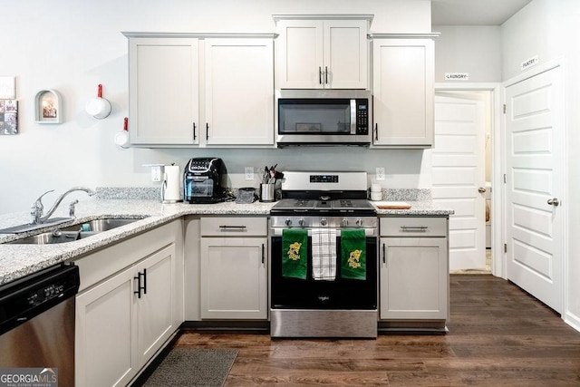 174 Silver Birch Pass, Newnan, GA 30265 - kitchen featuring appliances with stainless steel finishes, a sink, dark wood-style floors, and light stone countertops