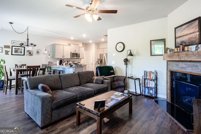 174 Silver Birch Pass, Newnan, GA 30265 - living room featuring a ceiling fan, a chandelier, dark wood-style flooring, a glass covered fireplace, and baseboards
