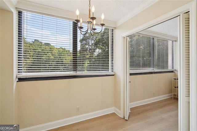 3530 Piedmont Rd NE Unit 2I, Atlanta, GA 30305 - unfurnished dining area with wood finished floors, a chandelier, ornamental molding, plenty of natural light, and a textured ceiling