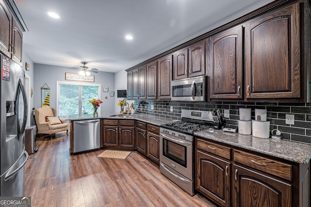 405 Dugas Rd, Dahlonega, GA 30533 - kitchen with appliances with stainless steel finishes, dark brown cabinetry, light wood-style floors, a ceiling fan, and backsplash