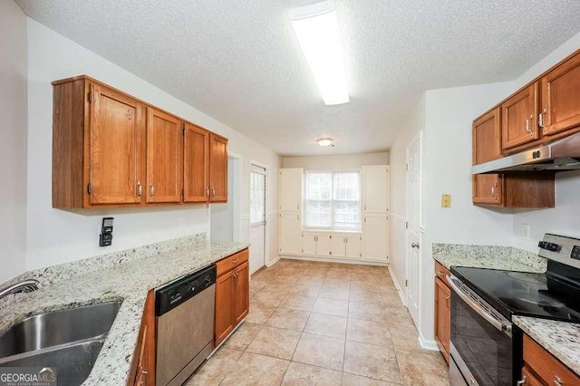 4112 Meadowlark Ct, Powder Springs, GA 30127 - kitchen with stainless steel appliances, under cabinet range hood, a sink, a textured ceiling, and brown cabinets