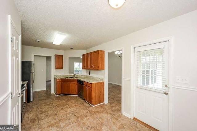 4112 Meadowlark Ct, Powder Springs, GA 30127 - kitchen featuring dishwashing machine, brown cabinets, freestanding refrigerator, a sink, and a textured ceiling