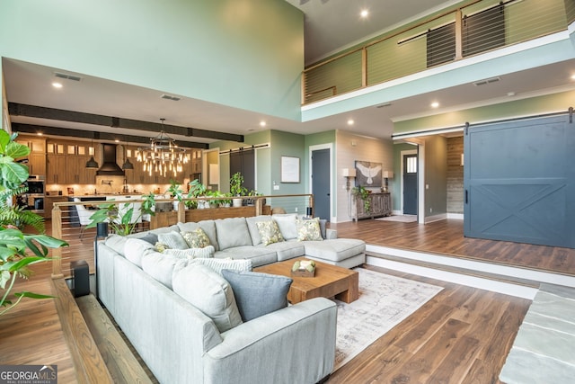 209 Voyles Way, Dawsonville, GA 30534 - living room with a barn door, a towering ceiling, wood finished floors, a chandelier, and recessed lighting