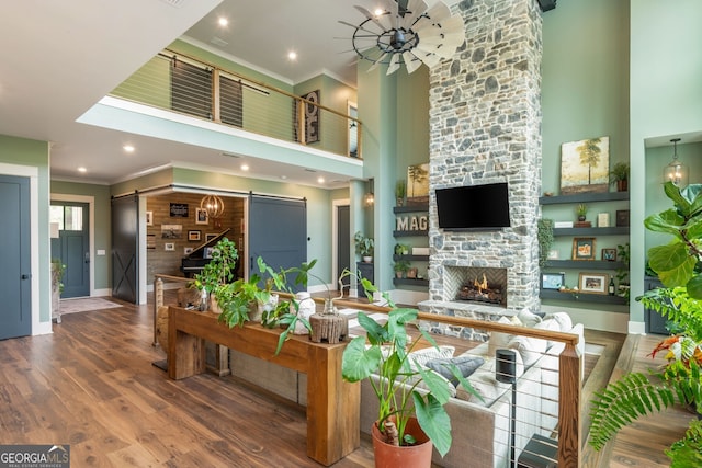 209 Voyles Way, Dawsonville, GA 30534 - living area featuring a barn door, a towering ceiling, crown molding, a fireplace, and wood finished floors