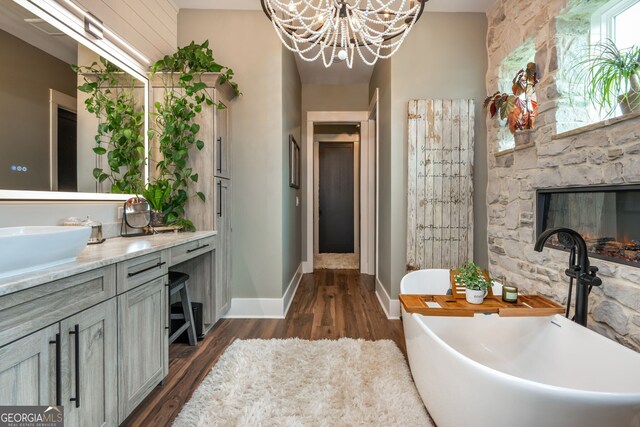 209 Voyles Way, Dawsonville, GA 30534 - bathroom with vanity, a freestanding bath, wood finished floors, a chandelier, and a stone fireplace