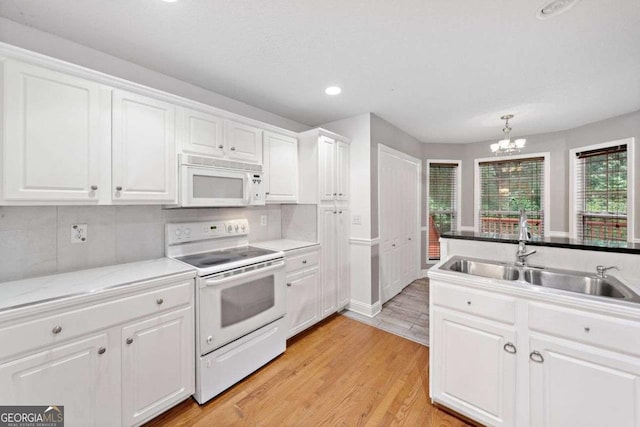 4544 Dorsett Shoals Run, Douglasville, GA 30135 - kitchen with white appliances, a chandelier, white cabinets, light wood-style flooring, and decorative backsplash