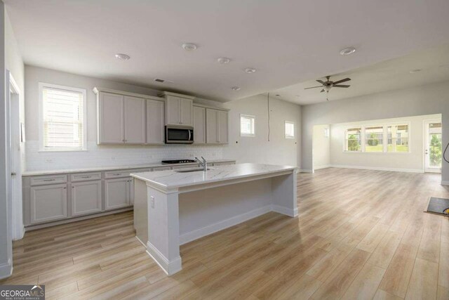 2856 Knob Creek Dr, Snellville, GA 30078 - kitchen featuring stainless steel microwave, a sink, light wood-type flooring, and ceiling fan