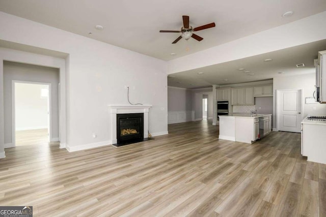 2856 Knob Creek Dr, Snellville, GA 30078 - unfurnished living room featuring ceiling fan, a fireplace with flush hearth, light wood-style flooring, baseboards, and a sink