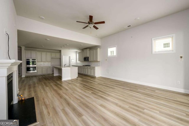 2856 Knob Creek Dr, Snellville, GA 30078 - unfurnished living room with ceiling fan, healthy amount of natural light, light wood-style floors, and a glass covered fireplace