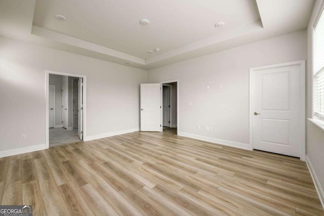 2856 Knob Creek Dr, Snellville, GA 30078 - unfurnished bedroom featuring a tray ceiling, light wood-style floors, baseboards, and multiple windows