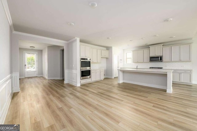 2856 Knob Creek Dr, Snellville, GA 30078 - kitchen featuring stainless steel appliances, light wood-type flooring, light countertops, decorative backsplash, and an island with sink