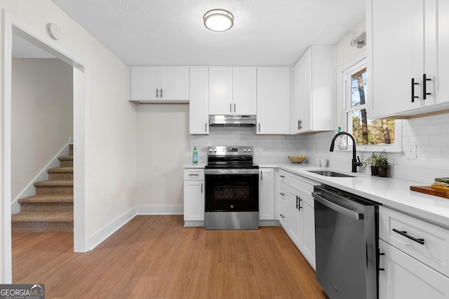 7000 Woodland Pl NW, Kennesaw, GA 30152 - kitchen with stainless steel appliances, under cabinet range hood, decorative backsplash, light wood-style floors, and light countertops