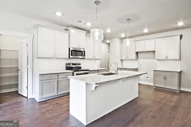 4063 Links Blvd, Jefferson, GA 30549 - kitchen with appliances with stainless steel finishes, a sink, decorative backsplash, light stone counters, and an island with sink