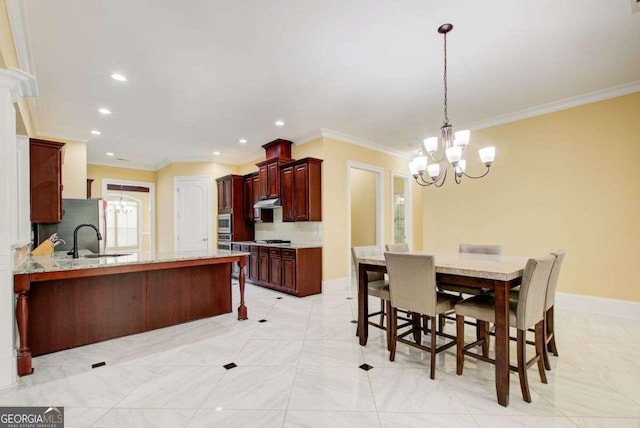 332 Warwick Pl, Mcdonough, GA 30253 - kitchen featuring a sink, a chandelier, a breakfast bar area, crown molding, and a peninsula