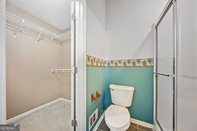 2623 Lone Oak Trl NW, Kennesaw, GA 30144 - bathroom with a walk in closet, a stall shower, toilet, and a textured ceiling