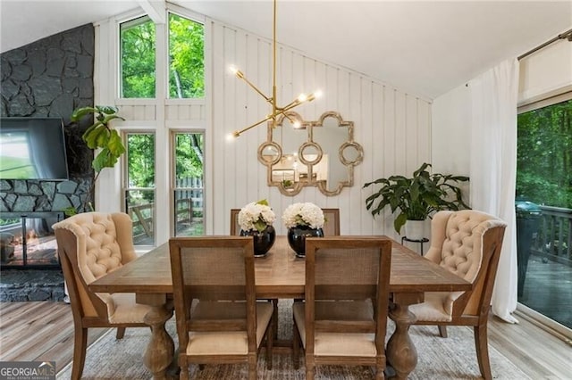 171 N Trce, Alpharetta, GA 30009 - dining space featuring wood finished floors, a chandelier, vaulted ceiling, and a fireplace