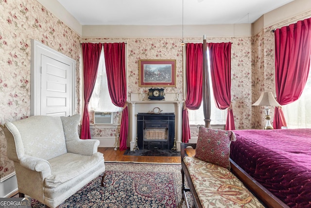 416 Engram St, Montezuma, GA 31063 - bedroom featuring wallpapered walls, multiple windows, wood finished floors, cooling unit, and a wood stove