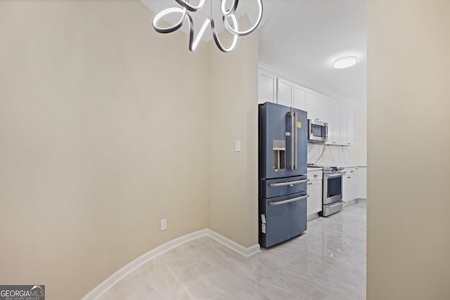2499 Peachtree Rd Unit 506, Atlanta, GA 30305 - kitchen featuring stainless steel appliances, a chandelier, white cabinets, decorative backsplash, and light marble finish floors