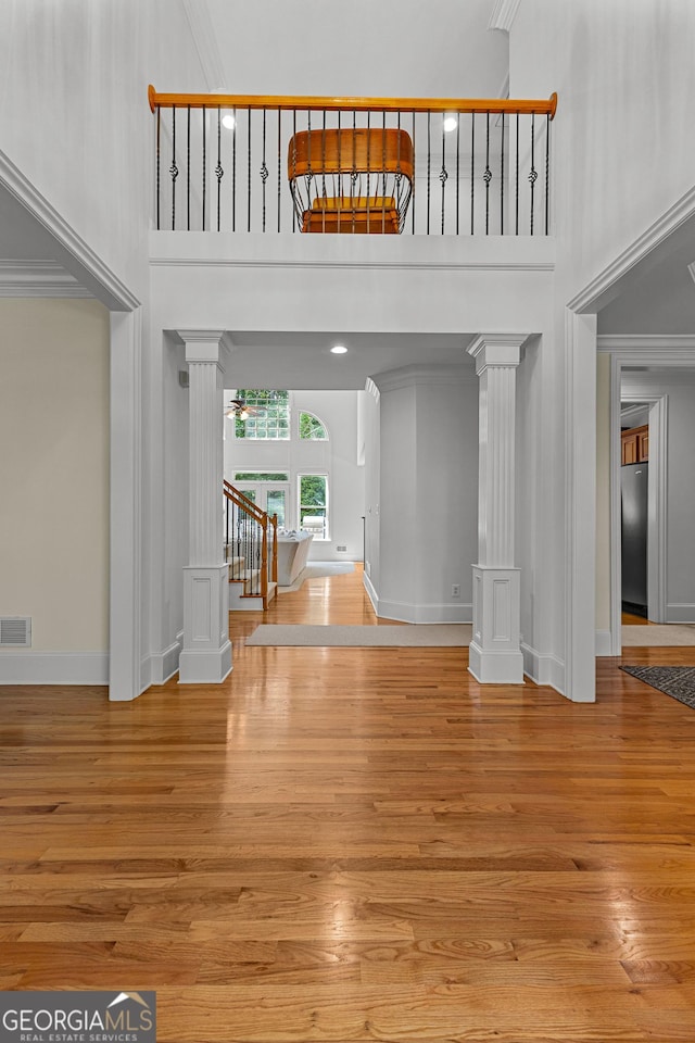 220 Broadmoor Dr, Fayetteville, GA 30215 - entryway with decorative columns, wood finished floors, a towering ceiling, crown molding, and baseboards