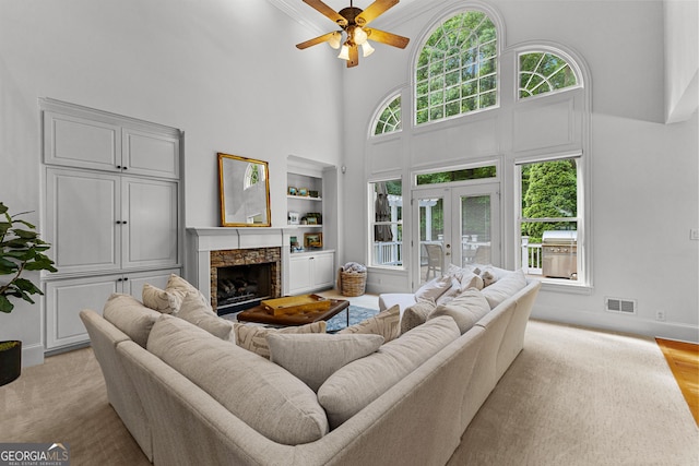 220 Broadmoor Dr, Fayetteville, GA 30215 - living area with a high ceiling, a ceiling fan, a stone fireplace, built in features, and french doors