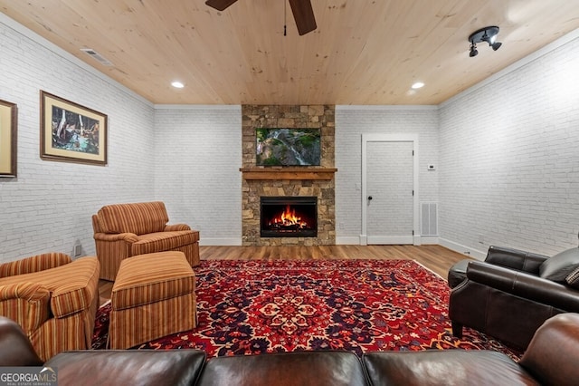 547 Toccoa River Ln, Mineral Bluff, GA 30559 - living area featuring ceiling fan, wood ceiling, a stone fireplace, brick wall, and wood finished floors