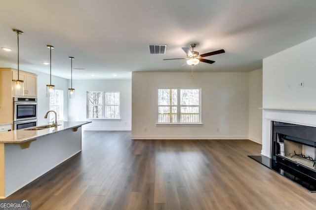 537 Principal Meridian Dr, Dallas, GA 30132 - unfurnished living room with a sink, ceiling fan, dark wood-style flooring, a fireplace with raised hearth, and baseboards