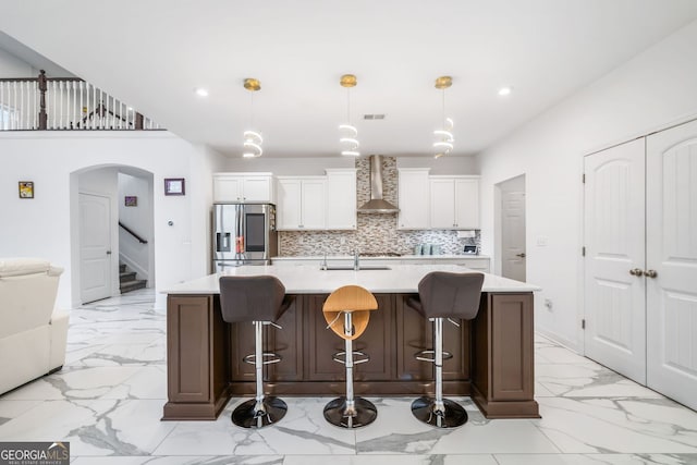 2121 Harmony Dr, Canton, GA 30115 - kitchen featuring stainless steel refrigerator with ice dispenser, light marble finish floors, wall chimney range hood, arched walkways, and light countertops
