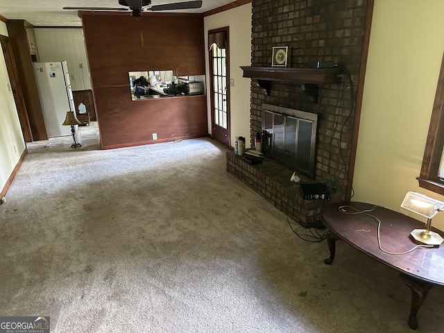 5125 Flakes Mill Rd, Ellenwood, GA 30294 - unfurnished living room with ceiling fan, carpet flooring, a fireplace, ornamental molding, and wood walls