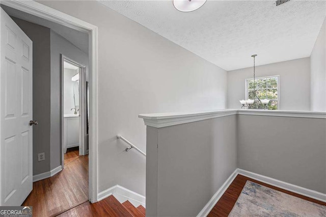 1047 Woodsong Pass Ct, Lawrenceville, GA 30043 - hall with an upstairs landing, wood finished floors, a textured ceiling, baseboards, and a chandelier