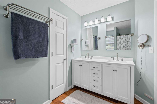 1047 Woodsong Pass Ct, Lawrenceville, GA 30043 - full bath featuring double vanity, wood finished floors, a shower with curtain, and baseboards