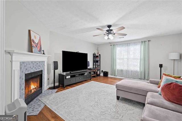 1047 Woodsong Pass Ct, Lawrenceville, GA 30043 - living room featuring a textured ceiling, a tiled fireplace, a ceiling fan, wood finished floors, and baseboards