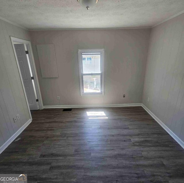 359 Hoyt St, Cornelia, GA 30531 - empty room featuring ornamental molding, a textured ceiling, dark wood-type flooring, baseboards, and wood walls
