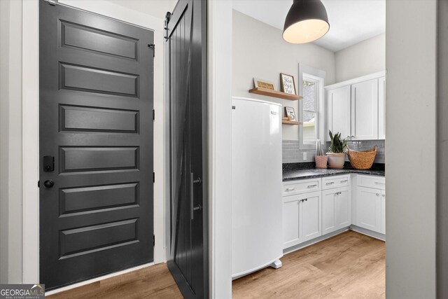 2490 S Carroll St, Villa Rica, GA 30180 - kitchen with white cabinetry, decorative backsplash, light wood finished floors, open shelves, and freestanding refrigerator