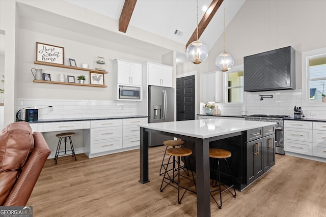 2490 S Carroll St, Villa Rica, GA 30180 - kitchen featuring appliances with stainless steel finishes, a kitchen bar, backsplash, white cabinets, and beamed ceiling