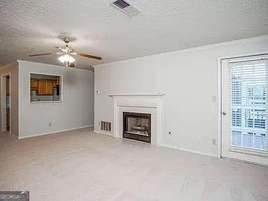 510 Berkeley Woods Dr, Duluth, GA 30096 - unfurnished living room with a textured ceiling, ceiling fan, a fireplace, crown molding, and carpet floors