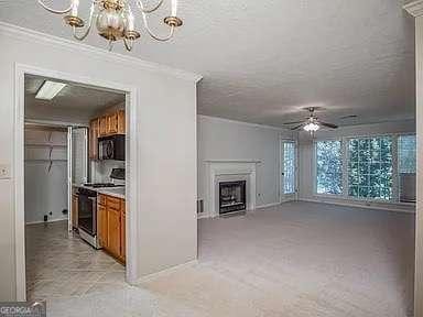 510 Berkeley Woods Dr, Duluth, GA 30096 - unfurnished living room featuring ornamental molding, a chandelier, a ceiling fan, baseboards, and a fireplace