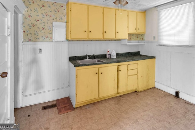 507 W 35th St, Savannah, GA 31415 - kitchen featuring a sink, a wainscoted wall, dark countertops, light floors, and wallpapered walls