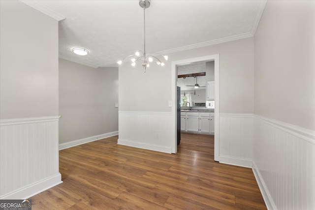 3357 Saddleton Way, Douglasville, GA 30134 - unfurnished dining area with wainscoting, dark wood finished floors, a chandelier, crown molding, and a sink