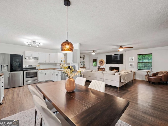 150 Archer Rd, Colbert, GA 30628 - dining room with a textured ceiling, a ceiling fan, light wood-style floors, and a fireplace