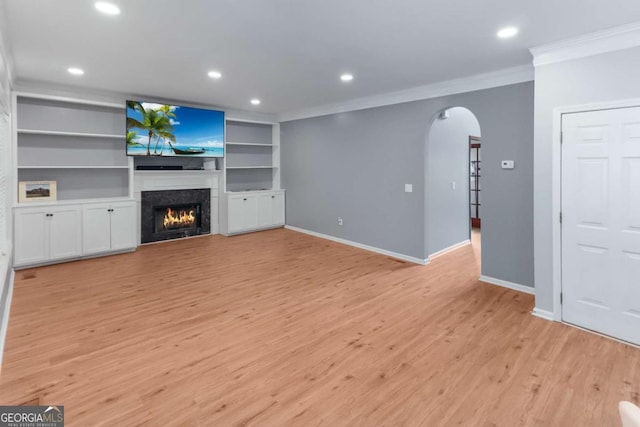 3898 Heritage Oaks Dr, Powder Springs, GA 30127 - unfurnished living room with ornamental molding, arched walkways, light wood finished floors, a warm lit fireplace, and recessed lighting