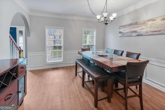 3898 Heritage Oaks Dr, Powder Springs, GA 30127 - dining space with a chandelier, light wood finished floors, ornamental molding, arched walkways, and a wainscoted wall