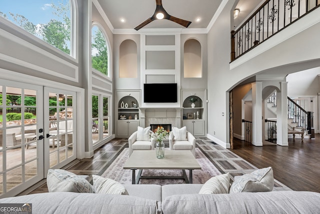 115 Hopewell Grove Dr, Milton, GA 30004 - living area with a high ceiling, built in shelves, a ceiling fan, stairs, and a warm lit fireplace