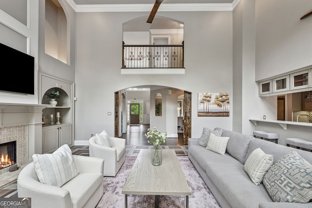 115 Hopewell Grove Dr, Milton, GA 30004 - living area featuring arched walkways, a tiled fireplace, wood finished floors, a towering ceiling, and baseboards